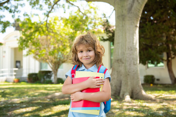 Pupil of primary school with book in hand. Portrait of the cute boy who is going to school with his school backpack. Beginning of lessons.