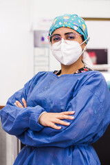 A portrait of a brunette female dentist in a clinic, with mask and gloves. Retrato de una dentista en una clinica, con mascarilla y gafas.