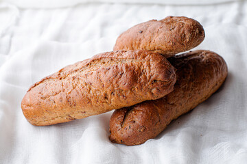 three freshly baked rye bread rolls on a white cloth napkin