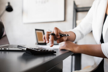  black business woman counts on a calculator and makes notes. financier or accountant works from home