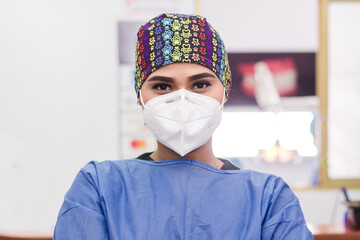 A portrait of a female dentist in her clinic with safety clothing and mask. Retrato de una dentista...