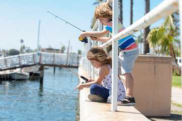 Couple of kids fishing on pier. Child at jetty with rod. Boy and girl with fish-rod.