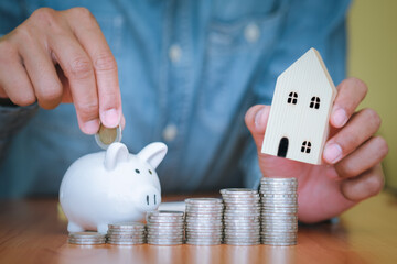 Business men put the coins into the white piggy bank and the coins stacks were lined up in front. The idea of ​​saving money to be used in the future. Financial and business concept