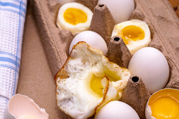eggs in a cardboard box on the table some eggs are whole others are in different degrees of readiness