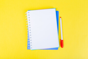 open spiral notepad on a yellow background with a pen. top view, stack of notepad with blank sheet. school concept, businessman work