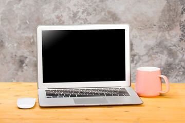 Fototapeta premium Mockup blank laptop screen with coffee on wooden table in coworking space.