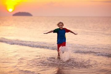 Child playing on ocean beach. Kid at sunset sea.
