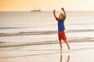 Child playing on ocean beach. Kid at sunset sea.