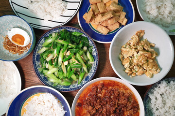 White rice served with stir-fry green vegetables, fried eggs, fried tofu and minced pork steamed eggs. Top view traditional Penang's home-cooked food. 