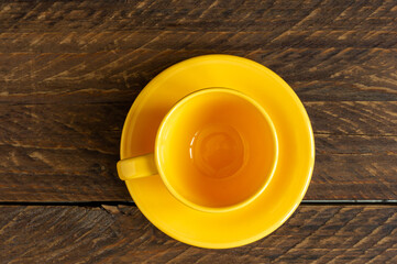 Top view of empty yellow cup and saucer on wooden rustic bckground. Kitchen crockery