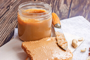 Homemade toasts  for breakfast with fresh crunchy peanut butter and nuts on light textile background.