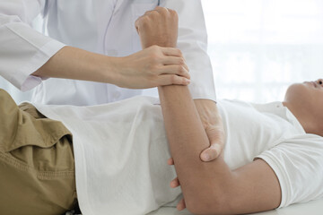 Female physiotherapists provide assistance to male patients with elbow injuries examine patients in rehabilitation centers. Physiotherapy concepts