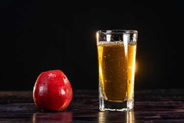 A ripe red apple and a tall glass of juice on a wooden background. close-up. healthy lifestyle. healthy eating. vitamins
