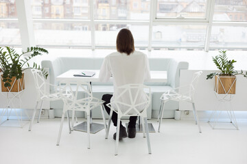 portrait of a business man working at a table in a laptop. phone and documents on the table. a man with a beard and long hair. filmed from behind
