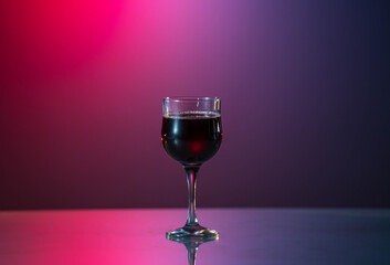 glass of red wine on the red-blue background. Good mood. Week end. Relax