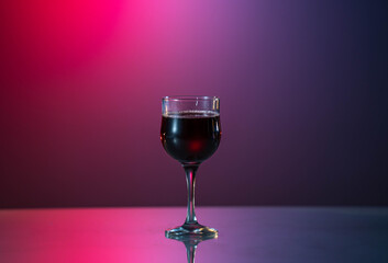 glass of red wine on the red-blue background. Good mood. Week end. Relax