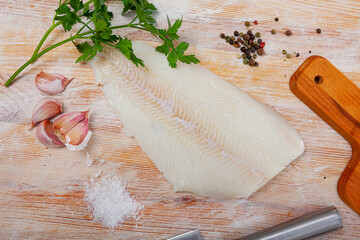 Fresh raw halibut fillet with greens and spices on wooden background. Cooking ingredients - obrazy, fototapety, plakaty