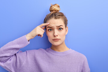 Thoughtful pensive young girl with hair bun making displeased grimace as if saying No
