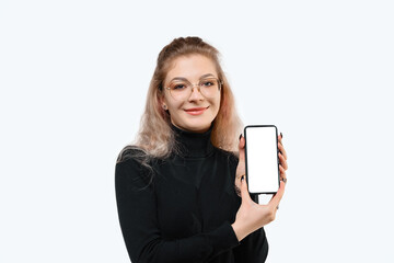 Fototapeta premium Smiling young woman showing empty smartphone screen to show advertisement, standing against white background