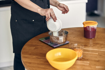 young beautiful mixed race woman is preparing marshmallow at light modern kitchen home
