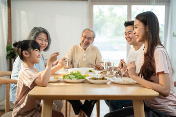 Obraz na płótnie Canvas Asian big family enjoy eating food together, sitting on dining table.