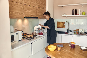 young beautiful mixed race woman is preparing marshmallow at light modern kitchen home