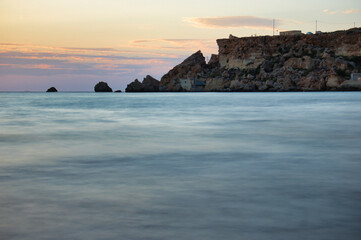 Rocky cliffs at Golden Bay with a puple sky at sunset on a warm fall evening in Malta.