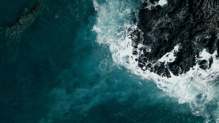 Aerial shot of waves crashing into a Hawaiian lava rock coast. drone