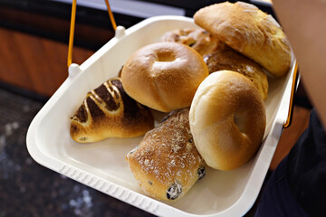 Close up of hands of female taking a tray of bread and pastry from the counter in a bakery store.
