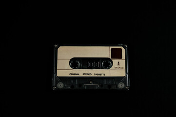 Obraz premium Audio cassette on a black background. Compact tape cassette an analog magnetic tape recording format for audio recording and playback. Copyright protection in the music industry.