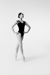 Young ballerina in black body suit on white background.	