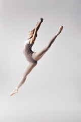 Young ballerina in black body posing in studio on white background.