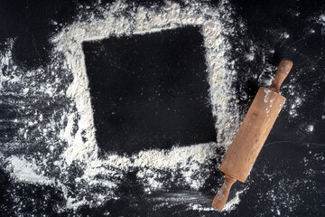 Baking frame with copy space, white flour and a wooden rolling pin