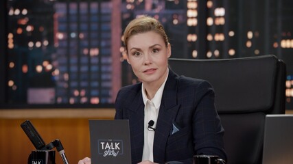 Portrait of late-night talk show female host having a conversation with celebrity guest in a...
