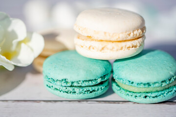 Selective focus. Turquoise and white macarons on light wooden background. French Pastel Macaroons. Blurred focus