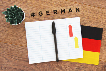 German flag, notebook, pen and inscription hashtag german on a wooden desktop, foreign language...