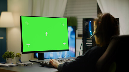 Pro gamer playing virtual video game on powerful computer with green screen mock up, chroma key display. Cyber player using professional pc with isolated desktop streaming shooter games wearing © DC Studio