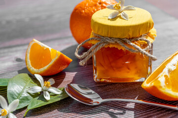 Traditional arrangement of orange jam with fresh orange fruits on wooden background. Still life. Minimal food concept. Harsh shadow. Flat lay