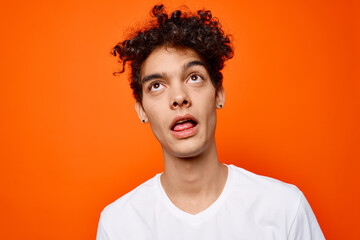 Cheerful guy in a white t-shirt emotion close-up orange background