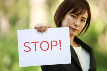 「STOP!」と書かれたメッセージボードを持つ女性社員