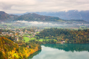 Scenic aerial view of Bled in Julian Alps at sunset, Slovenia. Amazing autumn landscape with emerald lake, sunny valley, alpine village and mountains, outdoor travel background