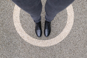 Black shoes standing in white circle on the asphalt concrete floor. Comfort zone or frame concept....