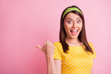 Photo of young beautiful smiling cheerful positive good mood positive girl pointing thumb in copyspace isolated on pink color background