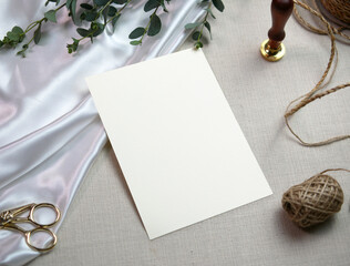 Top view mockup blank card, for greeting, wedding invitation template with eucalyptus leaves on cloth background. with clipping path.