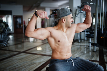 Fit and muscular arabian man doing workouts in gym.