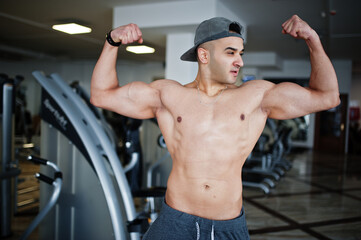 Fit and muscular arabian man doing workouts in gym.