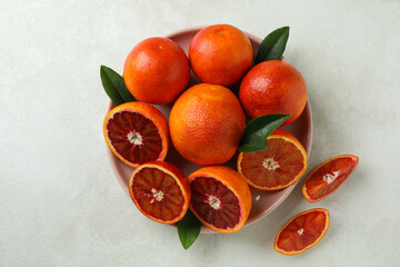 Plate with red oranges and leaves on white textured background