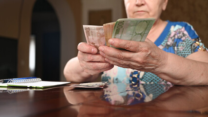 Close up of alderly woman holds banknotes euro, checks money savings, pension payments