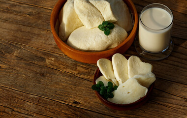 Cypriot semi-hard, fresh homemade unripened brined cheese halloumi in wooden plates and milk. popular in the Levant, Greece and Turkey.Side view in wicker busket on rustic wooden background,copy space