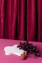 Vertical image of white stage for product presentation, grape and corckscrew on the pink surface...
